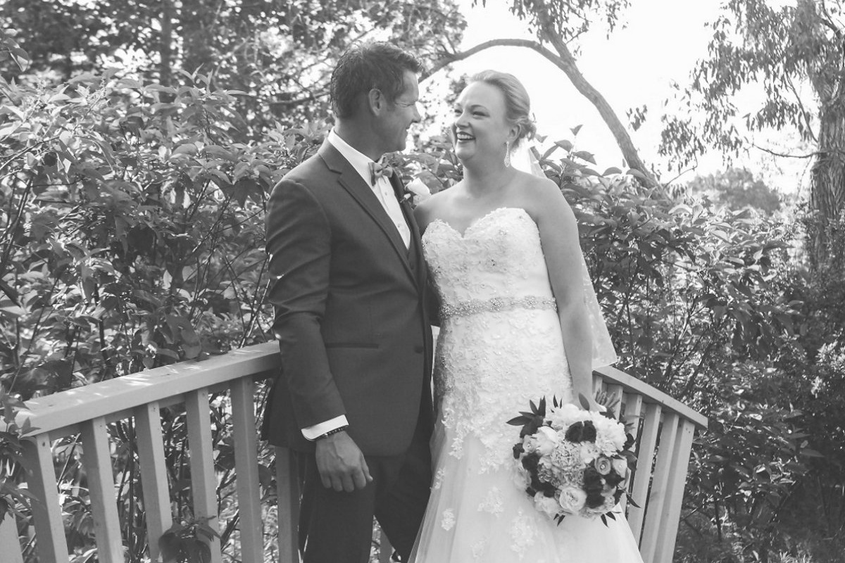 A male and female couple poses on their wedding day in a park