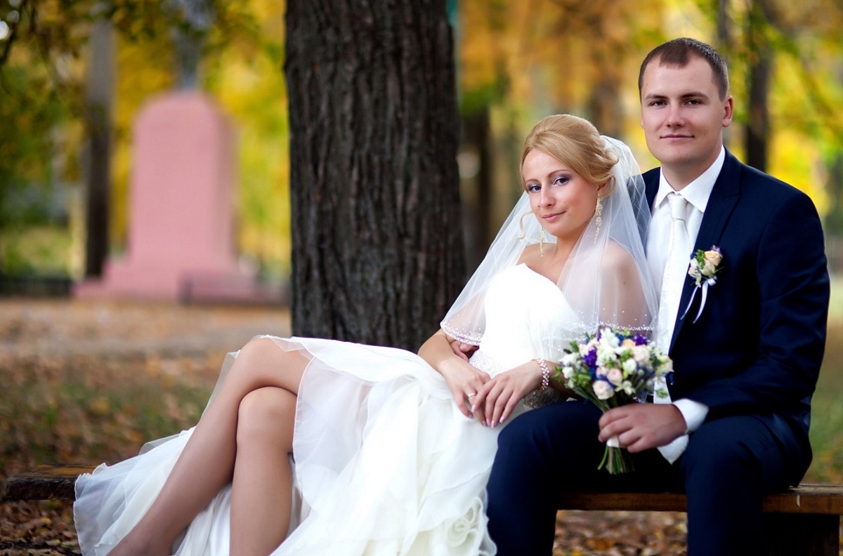 A male and female couple poses on their wedding day in a park