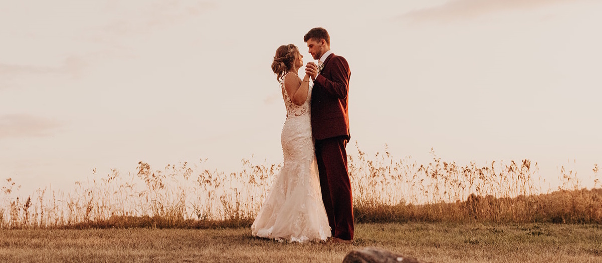 A male and female couple poses on their wedding day in a park