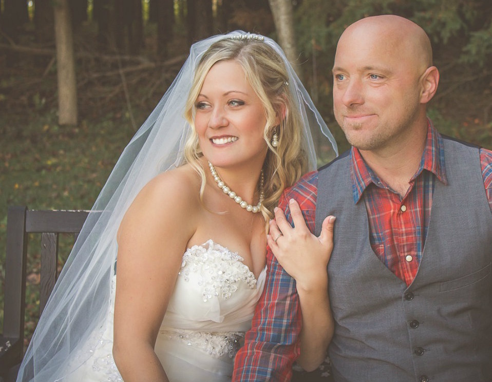 A male and female couple poses on their wedding day in a park